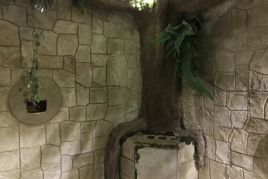 Arbre et racines sculptés, intégrés à un mur de pierre